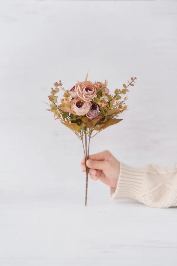 造花ブーケの一例。くすみカラーの花々を束ねたブーケを手に持った様子